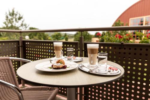 two tables with plates of food and drinks on a balcony at Vulkán Wellness Hotel & Camping in Celldömölk