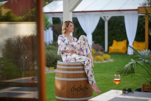 a woman sitting on a barrel with a glass of wine at ChaChaCha House Vendégház in Egerszalók