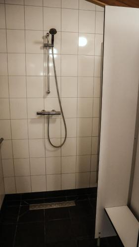 a shower with a hose in a white tiled bathroom at Camping Wijndomein Erve Wisselink in Eibergen