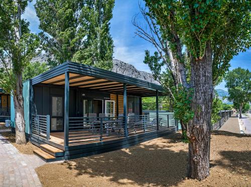 a house with a wooden porch with a tree at Camping Almissa in Omiš