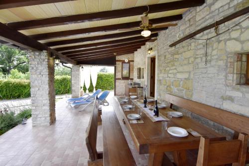 a dining room with a wooden table and a stone wall at Vila Vesna in Grožnjan