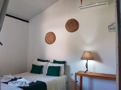 a bedroom with a bed with green pillows and a lamp at Pousada João Maria in Trancoso