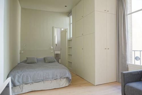 une chambre blanche avec un lit et une chaise dans l'établissement Rue Chateaubriand - Paris 8, à Paris