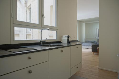 une cuisine avec des armoires blanches et un évier dans l'établissement Rue Chateaubriand - Paris 8, à Paris