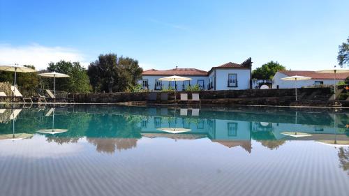 a swimming pool with chairs and umbrellas at Hotel Paço de Vitorino in Ponte de Lima