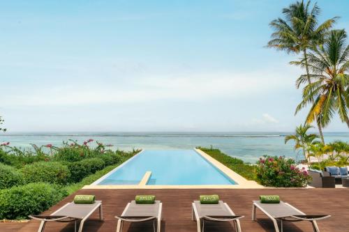 a pool with chairs and the ocean in the background at Melia Zanzibar in Kiwengwa