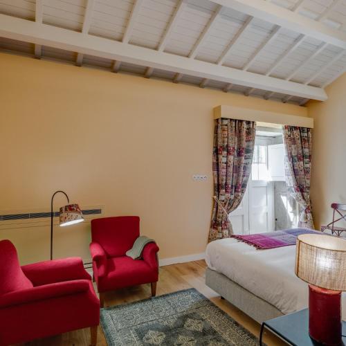 a bedroom with a bed and two red chairs at Hotel Paço de Vitorino in Ponte de Lima