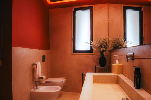 a bathroom with a tub and a toilet and two windows at Fiermonte Museum by La Fiermontina in Lecce
