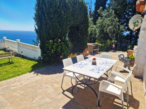 a table and chairs on a patio with the ocean at las flores in Almuñécar