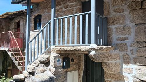 a stone building with a door and a balcony at Casa do Forno d'Aldeia in Mouços