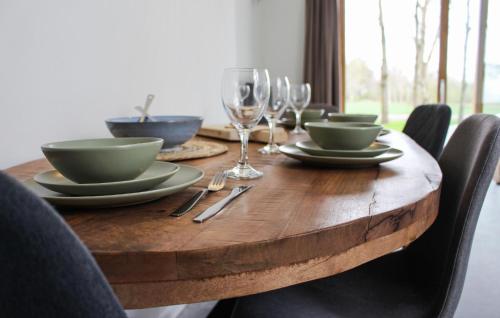 a wooden table with plates and wine glasses on it at Stunning Home In Ijhorst With Wifi in IJhorst