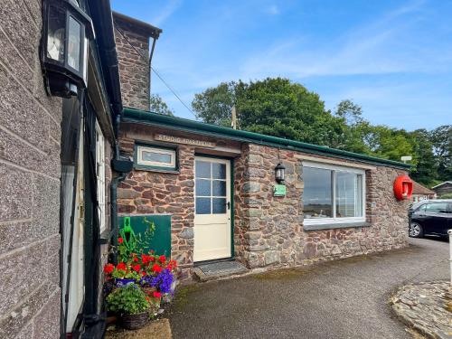 a stone house with a door and flowers in front of it at Harbour House Studio, Porlock Weir in Culbone