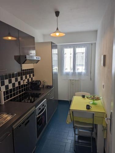une cuisine avec une table et un comptoir jaune dans l'établissement Charmant T1 au cœur de Nice, à Nice