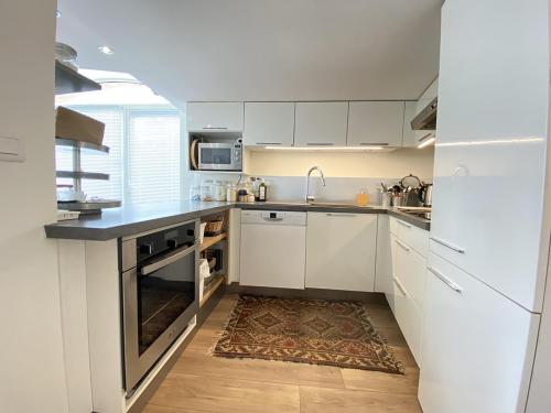 une cuisine avec des armoires blanches et un évier dans l'établissement L'Ecrin des bords de l'Erdre - Les Maisons de Madeleine, à Nantes