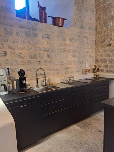 a kitchen with black cabinets and a sink at Chateau de Sainte Jalle in Sainte-Jalle