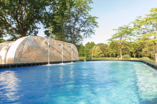 a swimming pool with a fountain in a park at Thermen Bad Nieuweschans in Bad-Nieuweschans