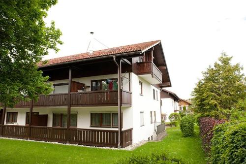 a large white building with a balcony and grass at Ferienwohnung Promenadenweg Nesselwang 14-8 in Nesselwang