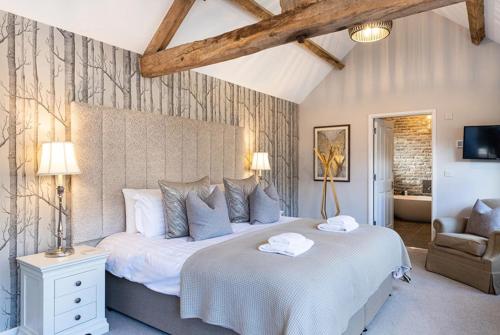 a bedroom with a large white bed and a chair at Beach Tree House in Gloucestershire