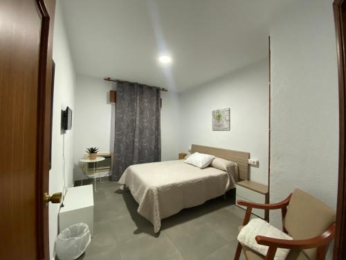 a small bedroom with a bed and a chair at Hotel Mu&ntilde;oz in Motril