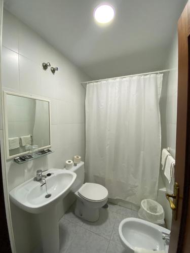 a white bathroom with a sink and a toilet at Hotel Mu&ntilde;oz in Motril