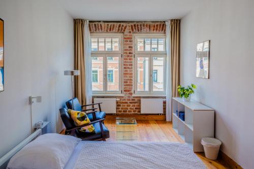 a bedroom with a bed and a chair and a window at Hostel Multitude in Leipzig