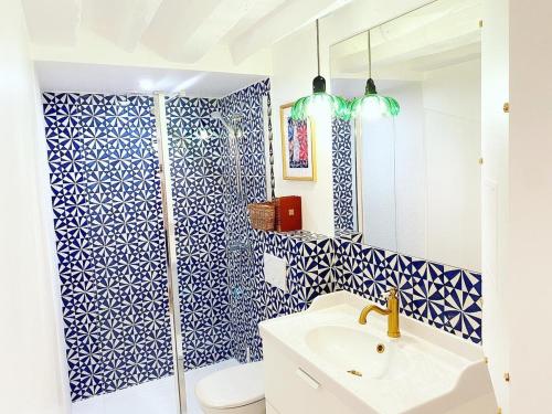 La salle de bains bleue et blanche est pourvue d'une douche et d'un lavabo. dans l'établissement Charmant appartement a Paris - FLAT-GUEST, à Paris