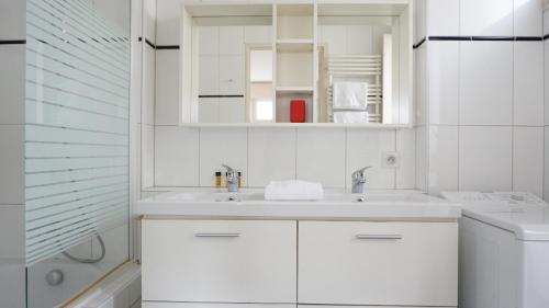 une salle de bain blanche avec un lavabo et une douche dans l'établissement Rue Lauriston - Paris 16, à Paris