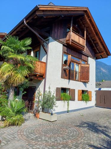 a house with a balcony and a palm tree at Neuprantl Apartments in Lana