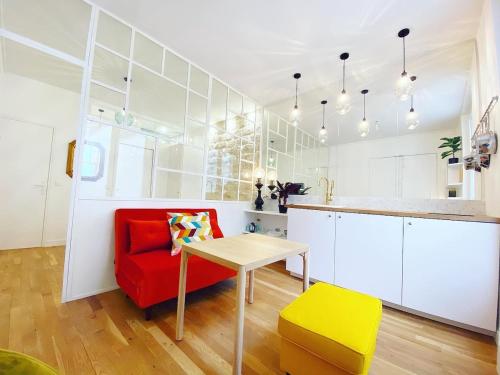 un salon avec une chaise rouge et une table dans l'établissement Tres bel appartement au coeur de Paris - FLAT-GUEST, à Paris