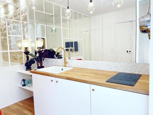 - une cuisine blanche avec un évier et un miroir dans l'établissement Tres bel appartement au coeur de Paris - FLAT-GUEST, à Paris