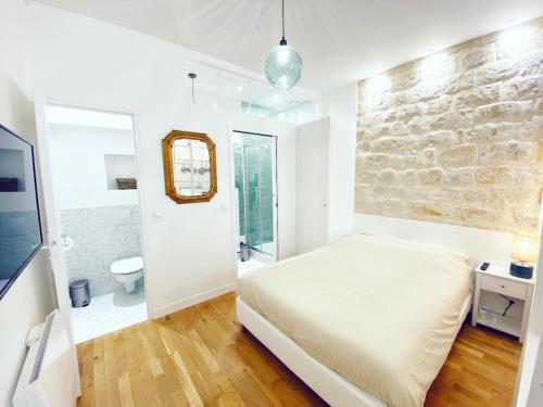 une chambre avec un lit blanc et un mur en pierre dans l'établissement Tres bel appartement au coeur de Paris - FLAT-GUEST, à Paris