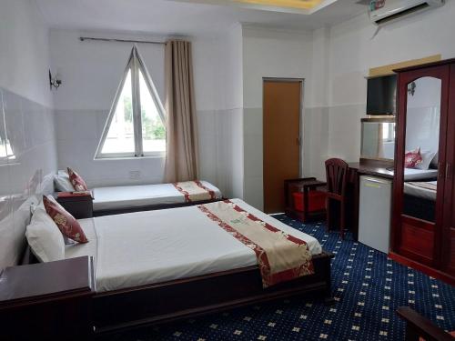 a hotel room with two beds and a window at Nhat Quy Hotel in Tây Ninh