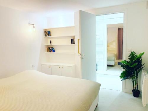 une chambre blanche avec un lit et un miroir dans l'établissement Appartement de standing a Paris - FLAT-GUEST, à Paris