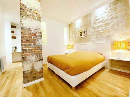 une chambre avec un lit et un mur de briques dans l'établissement Sublime loft au coeur de Paris 10 - FLAT-GUEST, à Paris