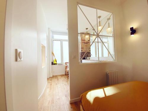 Cette chambre comprend un lit, un miroir et une fenêtre. dans l'établissement Magnifique appartement a Paris - FLAT-GUEST, à Paris