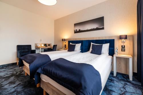 a hotel room with two large beds with blue covers at Ignasiak Hotel in Września