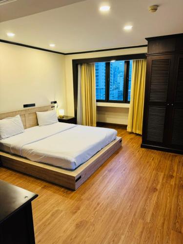 a bedroom with a bed and a large window at Affordable Serviced Apartment Nana - Omni Tower Sukhumvit location in Bangkok