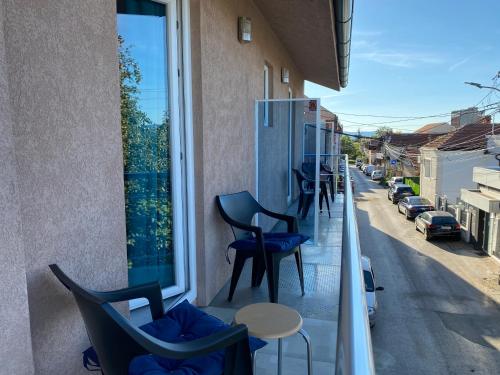 a balcony with chairs and tables on a street at Apartments and Rooms Radivojević Niš in Niš