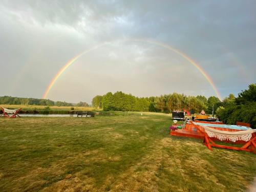 a rainbow in the sky over a field with a boat at Żurawi Staw- siedlisko obok Augustowa in Augustów