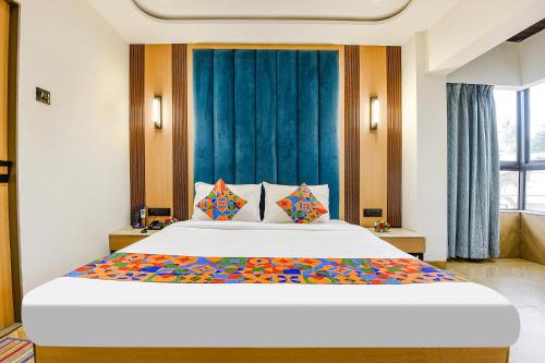 a bedroom with a large white bed with colorful pillows at Hotel Supreme - 700M From Vasco Da Gama Railway Station in Marmagao