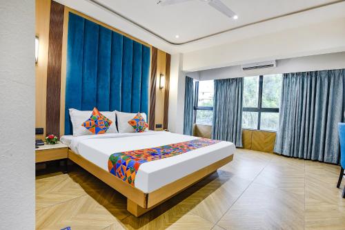 a bedroom with a large bed with blue curtains at Hotel Supreme - 700M From Vasco Da Gama Railway Station in Marmagao