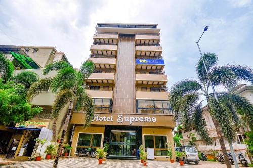 a tall building with palm trees in front of it at Hotel Supreme - 700M From Vasco Da Gama Railway Station in Marmagao