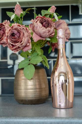 a gold vase with pink roses and a bottle at Pottery Place - Pet-friendly Huddersfield House Sleeps 7 in Huddersfield