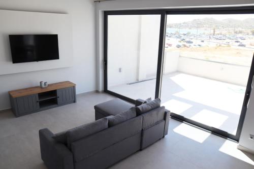 a living room with a couch and a tv at Golden Sand Suites 2 in Anavissos