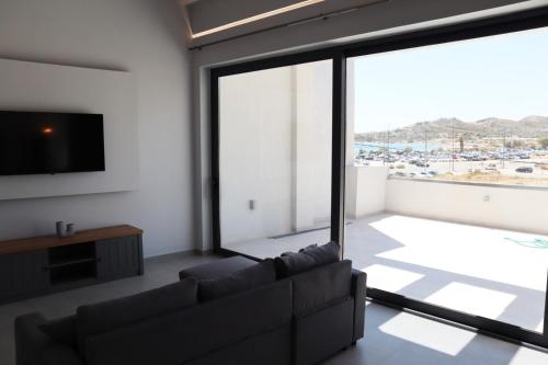 a living room with a couch and a large window at Golden Sand Suites 2 in Anavissos