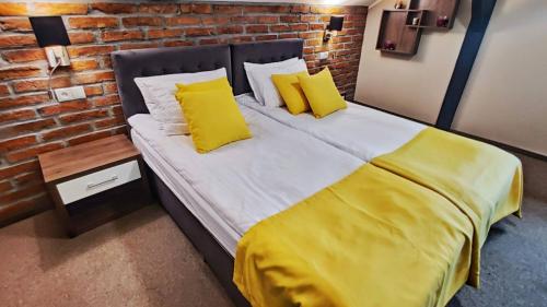 a bed with yellow pillows and a brick wall at Ignasiak Hotel in Września