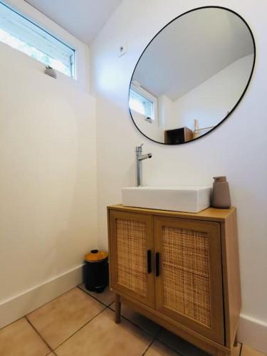 une salle de bain avec un lavabo et un miroir au mur dans l'établissement Gîte bohème à 5 min de la plage, à Loc-Maria-Plouzané