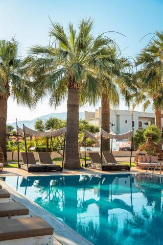 a pool with palm trees and lounge chairs at Ammos Boutique Apartments & Suites in Malia
