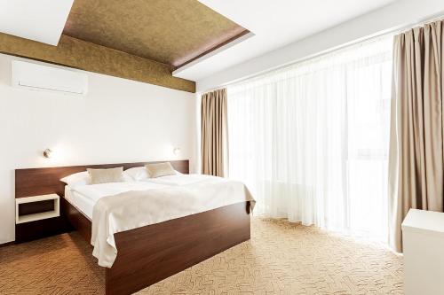 a hotel room with a bed and a large window at Hotel Šariš in Bardejov