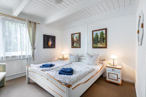 a white bedroom with a bed and two lamps at Atlanta Pur in Pellworm